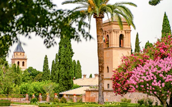 Generalife Gardens view with historic tower and lush greenery in Granada, Spain.