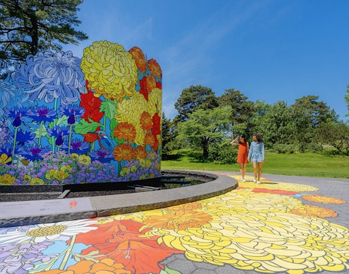 Guests walking by colorful floral mural at New York Botanical Garden.