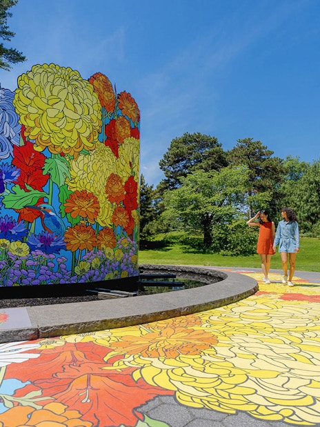 Guests walking by colorful floral mural at New York Botanical Garden.