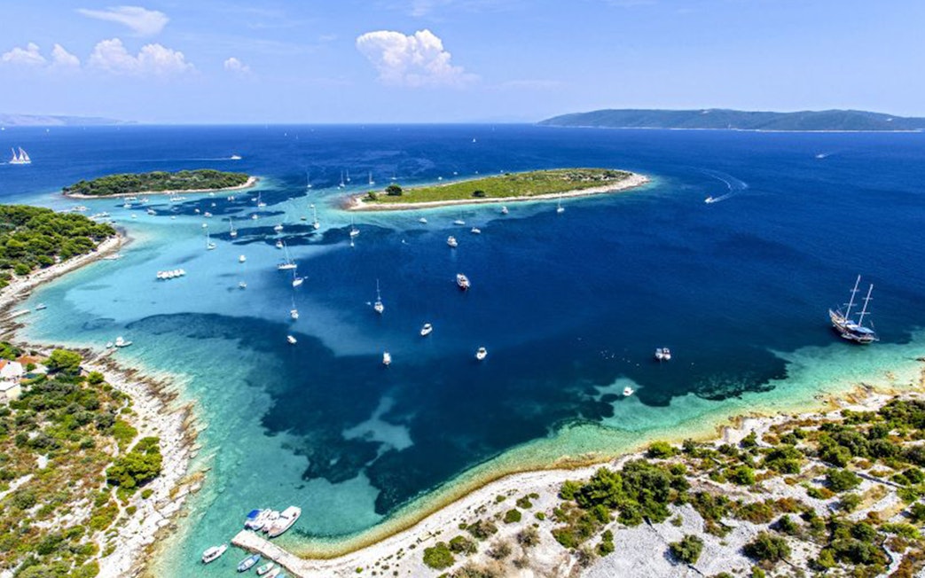 Boats anchored near islands in Blue Lagoon, Croatia, part of the Small Group 3 Islands tour.