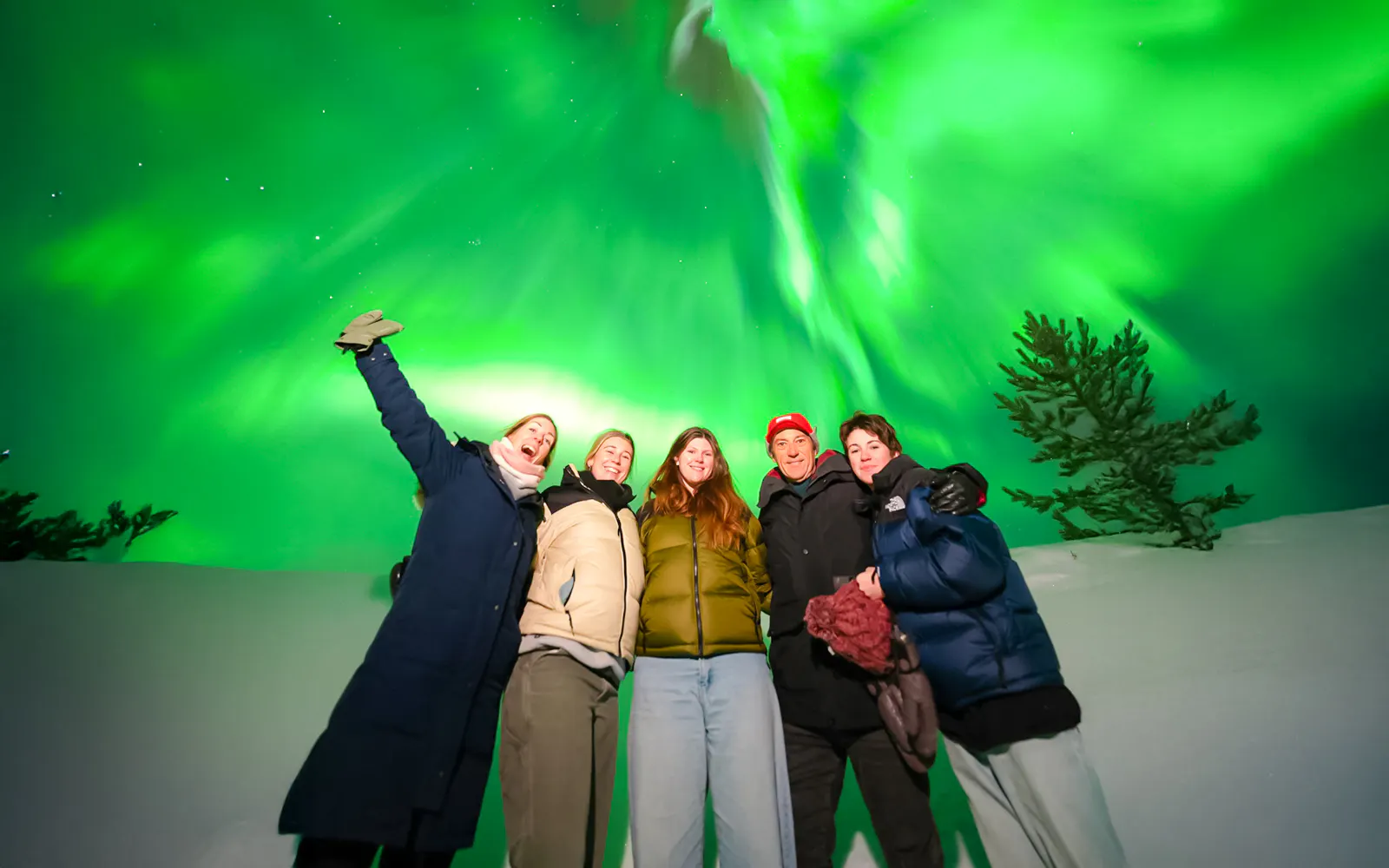 Guests on Northern Lights Chase Bus Tour in Rovaniemi under vibrant aurora borealis.