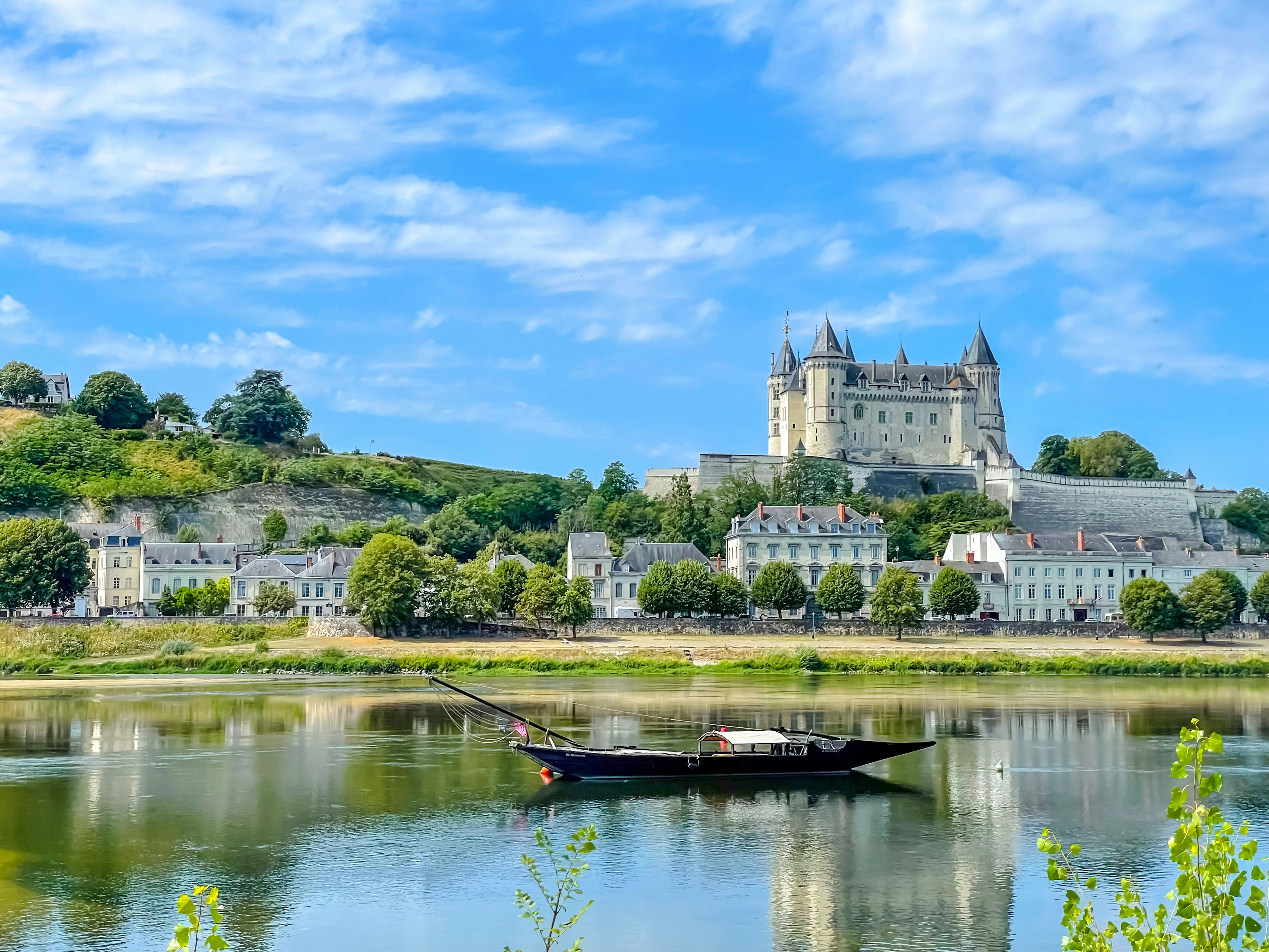 Cruise boat on the Loire River with Saumur Castle in the background, France.