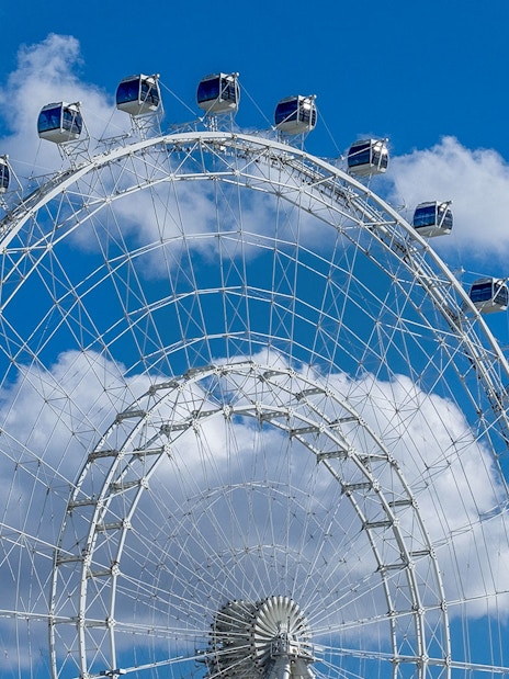 Ferris wheel cabins at The Wheel at ICON Park against a blue sky.