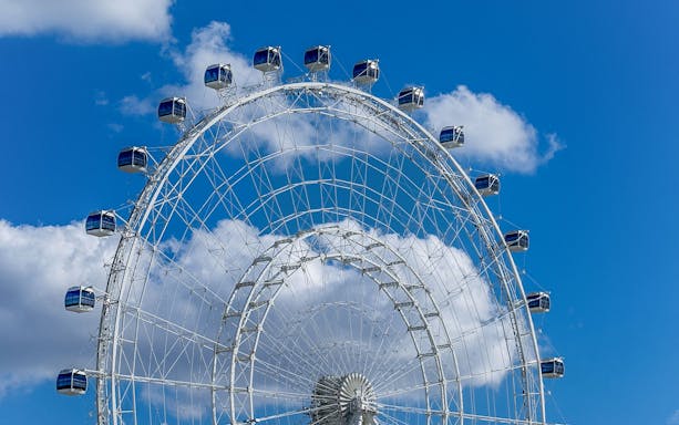 Ferris wheel cabins at The Wheel at ICON Park against a blue sky.