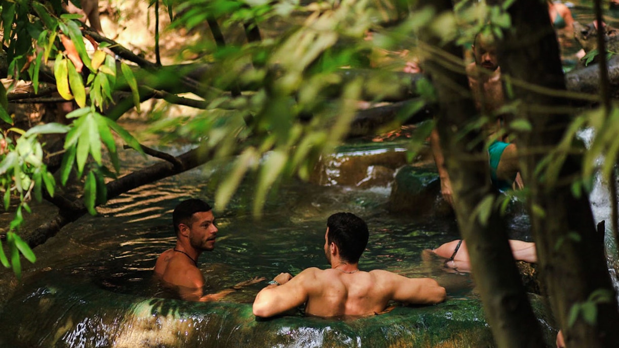 Tourists relaxing in the emerald pool surrounded by lush greenery in Krabi, Thailand.