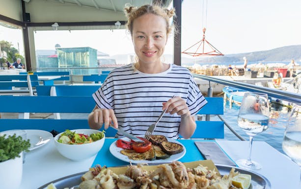 Tourist enjoying seafood meal at a waterfront restaurant in Croatia.