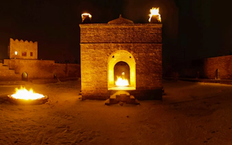 Azerbaijan's Ateshgah Fire Temple at night with flames, part of Baku: Gobustan - Absheron Tour.
