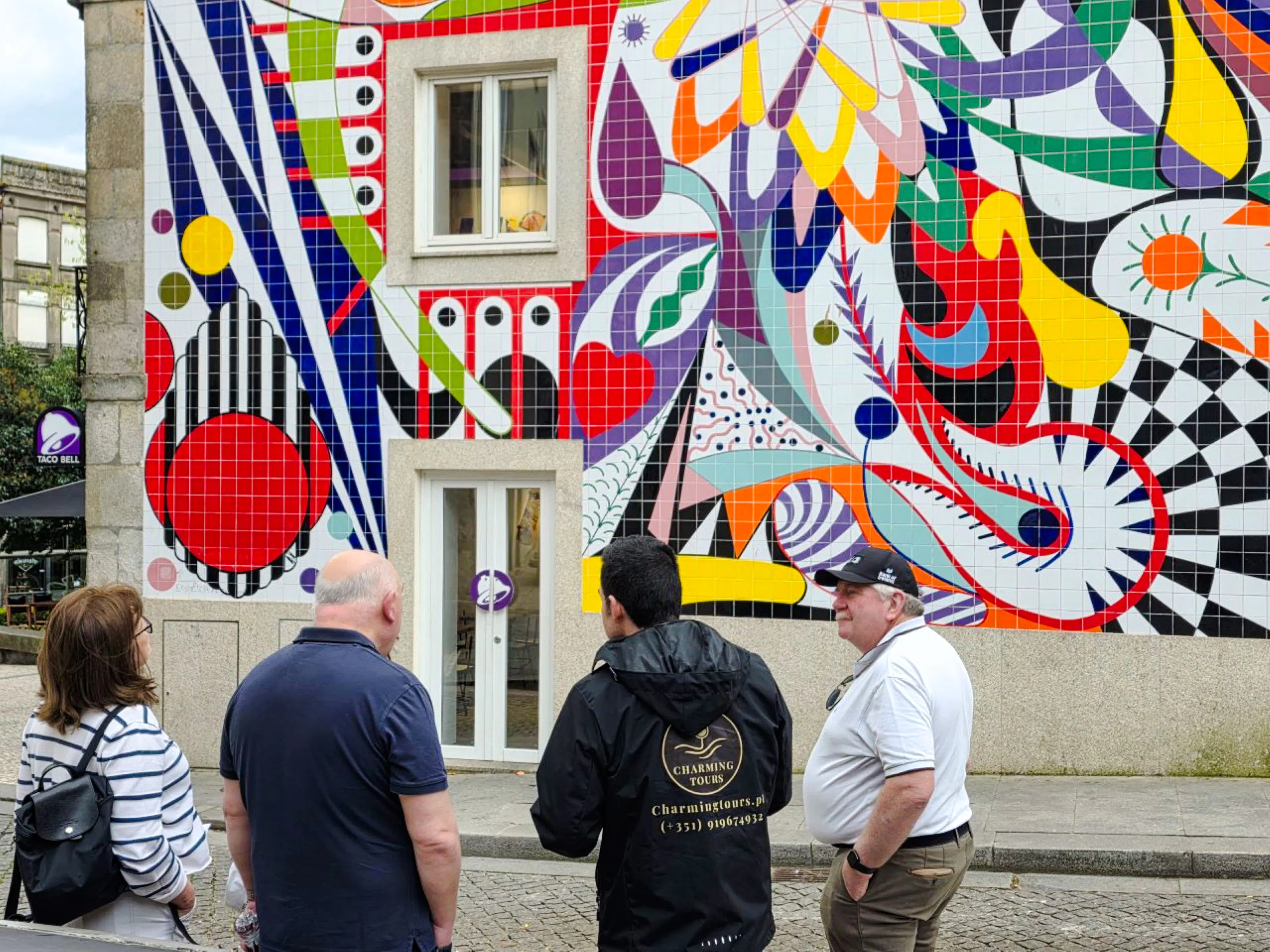 Tour group in Porto observing colorful tiled mural on walking tour.