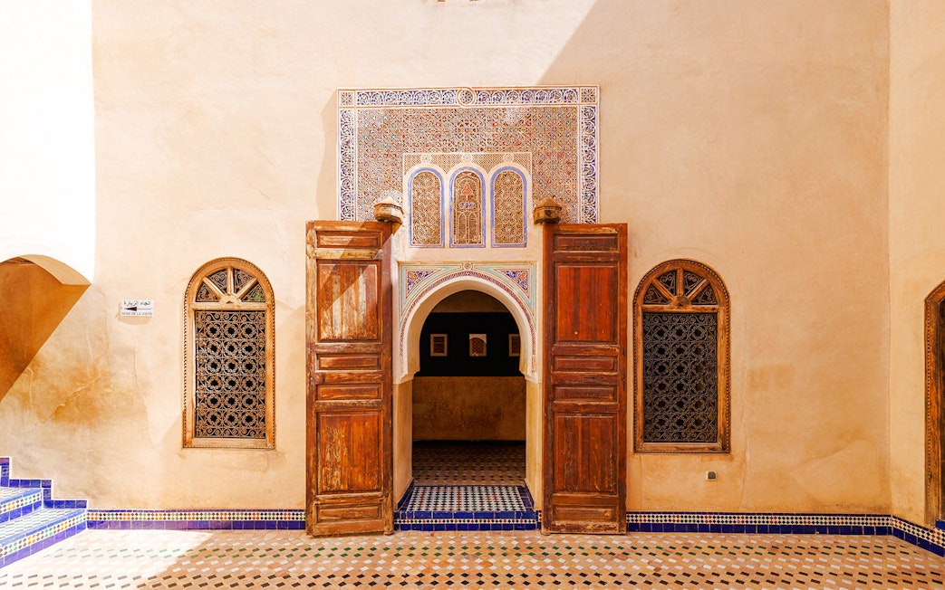 Ornate entrance with wooden doors and mosaic tiles at Bahia Palace, Marrakech, Morocco.
