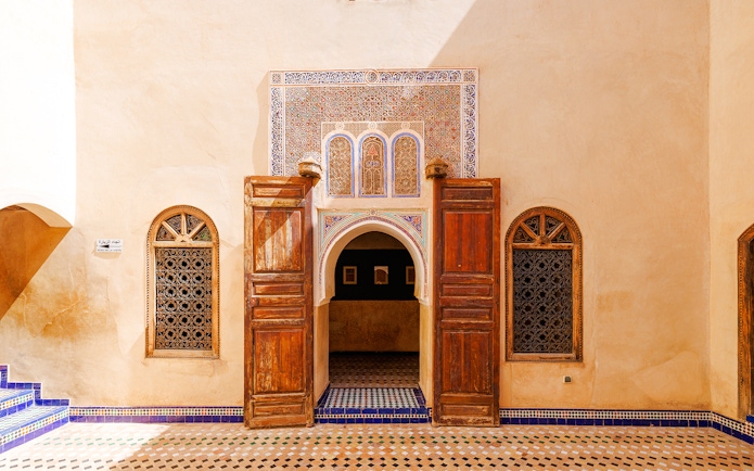 Ornate entrance with wooden doors and mosaic tiles at Bahia Palace, Marrakech, Morocco.