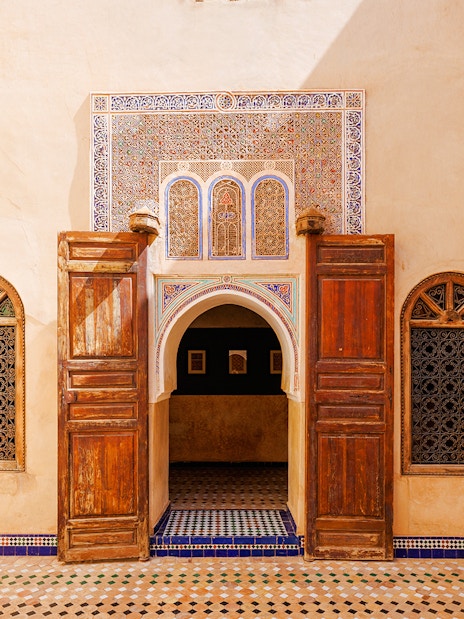 Ornate entrance with wooden doors and mosaic tiles at Bahia Palace, Marrakech, Morocco.