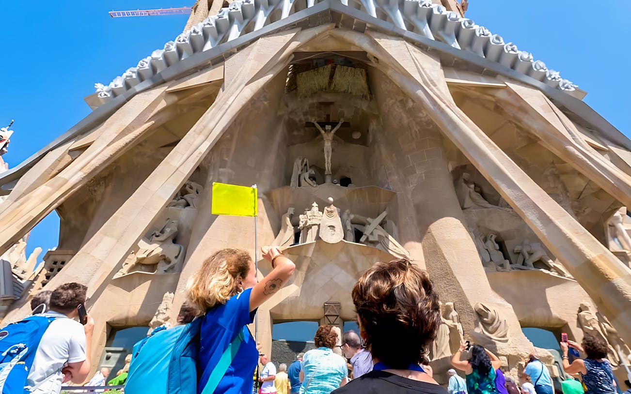 Tourist with guide outside Sagrada Familia, Barcelona, discussing architectural details.