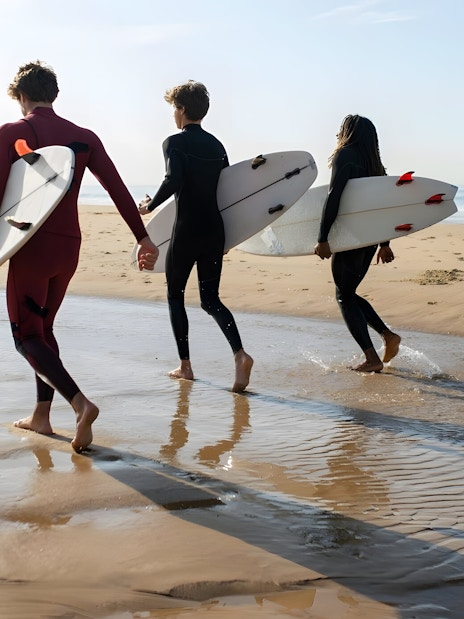 Tourists with surfboards walking on a beach after a surf class in Lisbon.