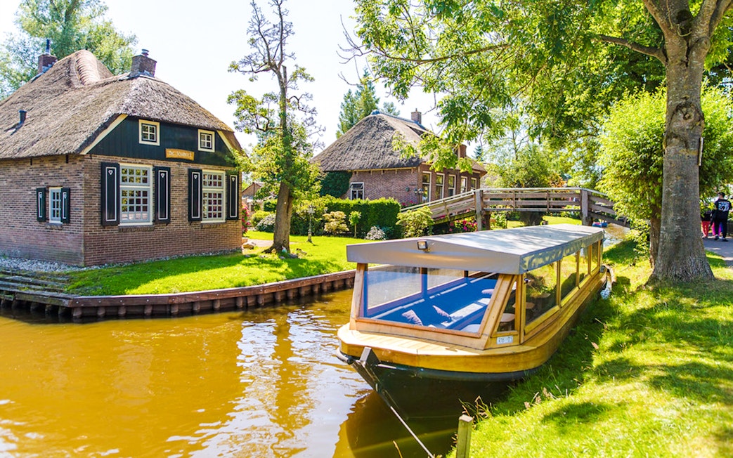 Canal boat near traditional thatched houses in Giethoorn, Netherlands.