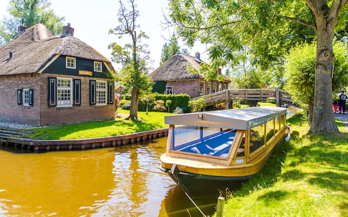 Canal boat near traditional thatched houses in Giethoorn, Netherlands.