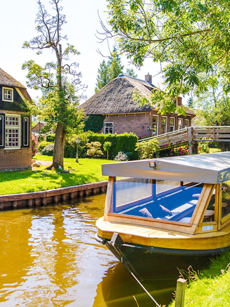 Canal boat near traditional thatched houses in Giethoorn, Netherlands.