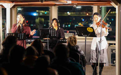 Live music performance on Eland Cruise, Seoul, featuring a singer, keyboardist, and violinist.