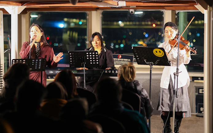 Live music performance on Eland Cruise, Seoul, featuring a singer, keyboardist, and violinist.