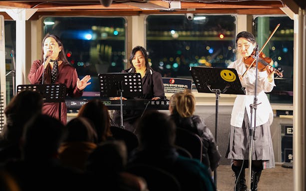 Live music performance on Eland Cruise, Seoul, featuring a singer, keyboardist, and violinist.