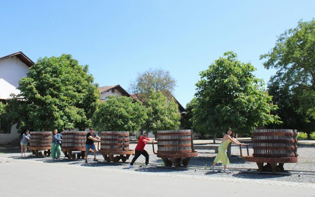 Visitors pushing historic wine barrels at Santa Rita Vineyard, Chile.