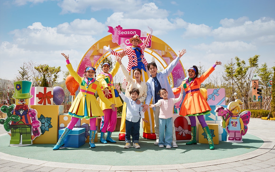 Family enjoying Legoland Korea with colorful performers and LEGO decorations.