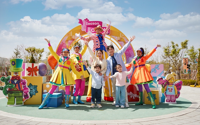 Family enjoying Legoland Korea with colorful performers and LEGO decorations.