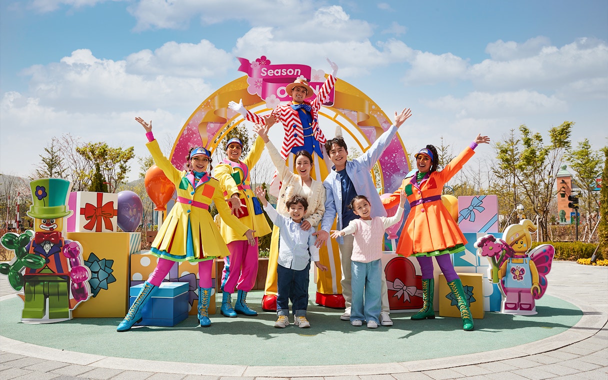 Family enjoying Legoland Korea with colorful performers and LEGO decorations.