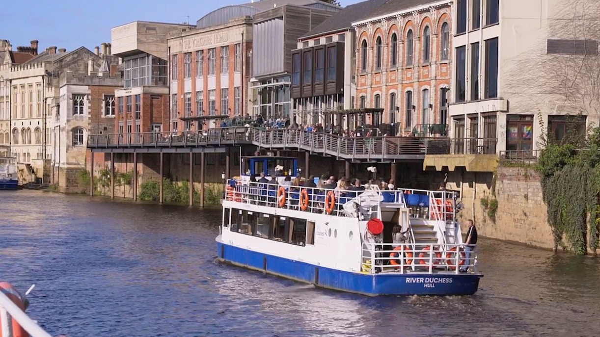 River cruise boat on the River Ouse passing historic buildings in York.