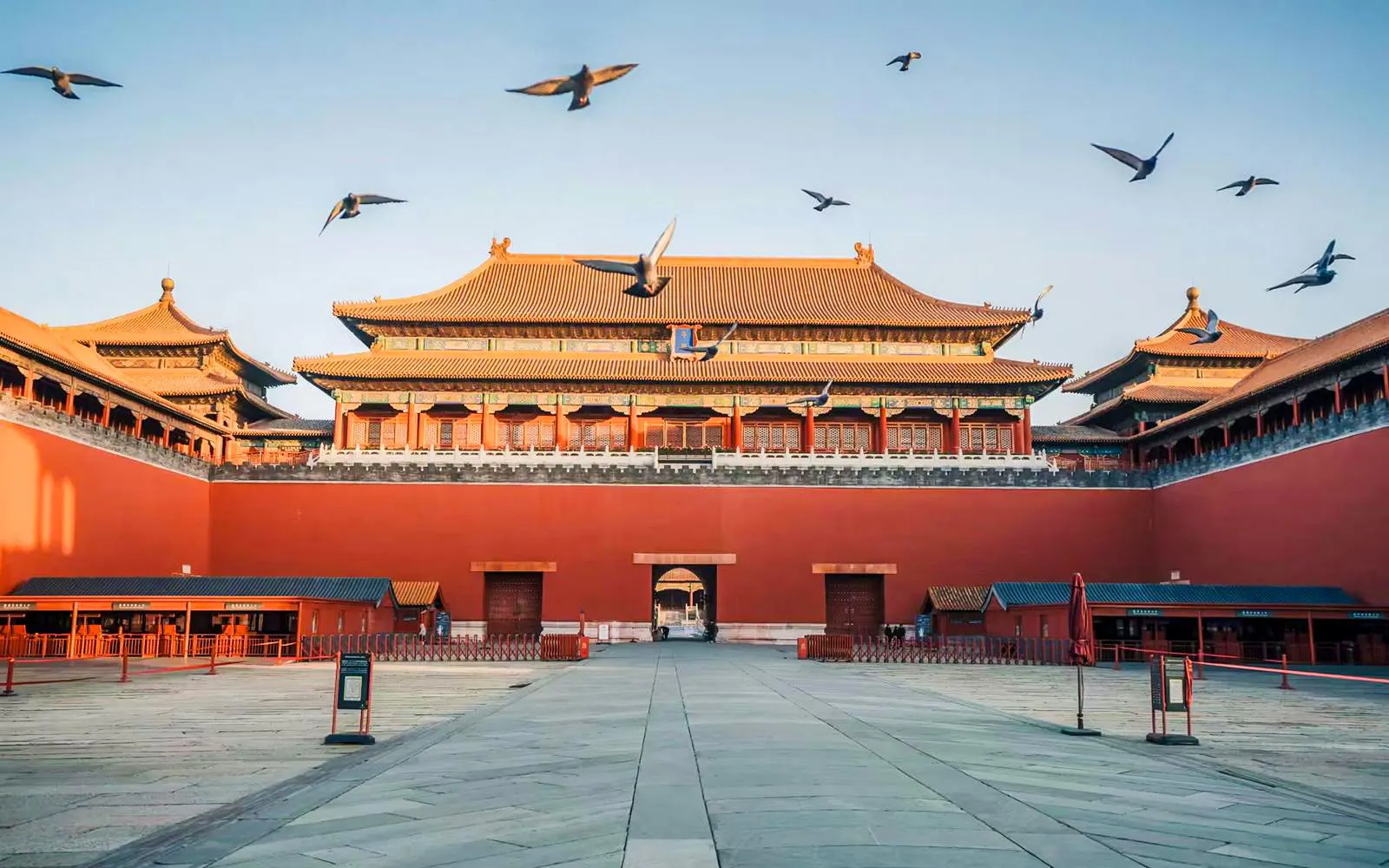 Meridian Gate of the Forbidden City in Beijing with birds flying overhead.