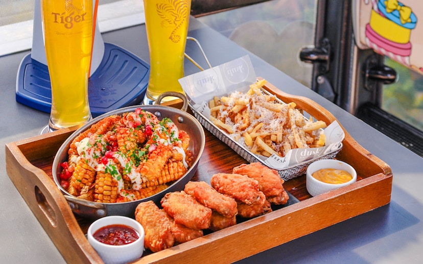 Dining tray with chicken wings, corn, fries, and beer in Singapore cable car sky dining, beer cabin.