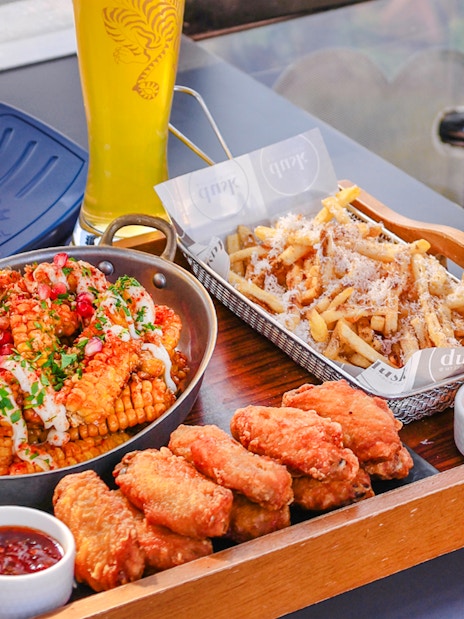 Dining tray with chicken wings, corn, fries, and beer in Singapore cable car sky dining, beer cabin.