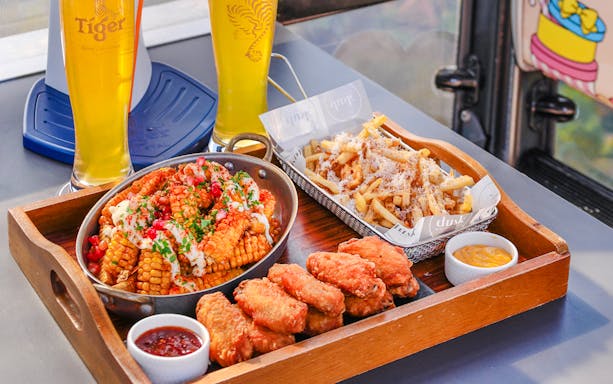Dining tray with chicken wings, corn, fries, and beer in Singapore cable car sky dining, beer cabin.