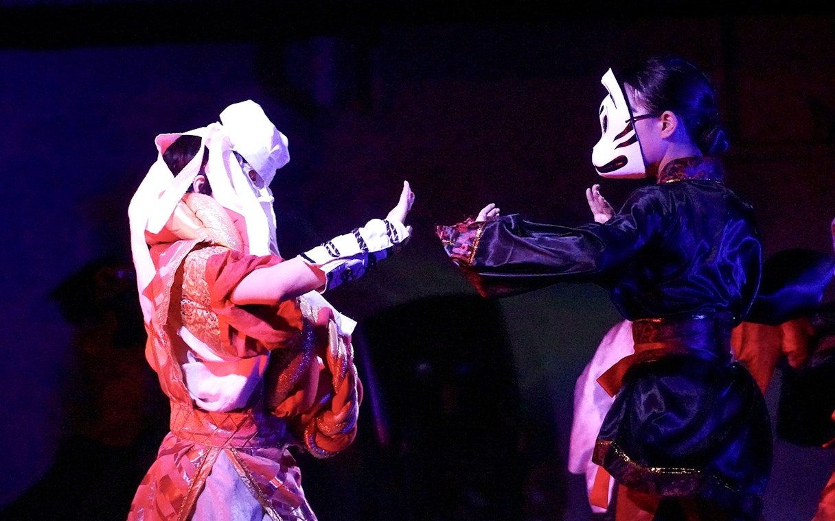 Performers in traditional costumes and masks at a Japanese festival dance show near Tokyo Tower.