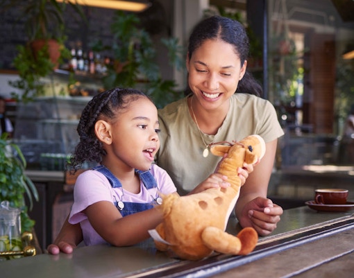 Child and adult enjoying a giraffe plush toy
