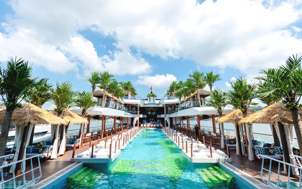 Pool area on Dolphin cruise ship with palm trees and cabanas.