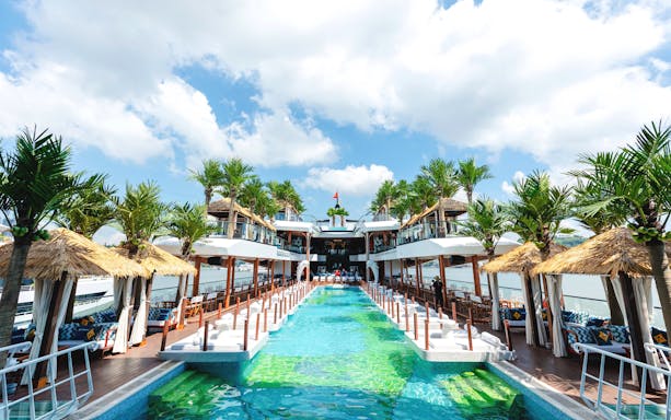 Pool area on Dolphin cruise ship with palm trees and cabanas.