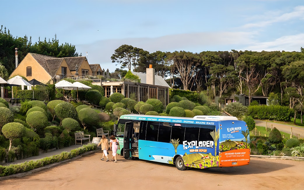 Waiheke Island hop on hop off tour bus near vineyard estate.