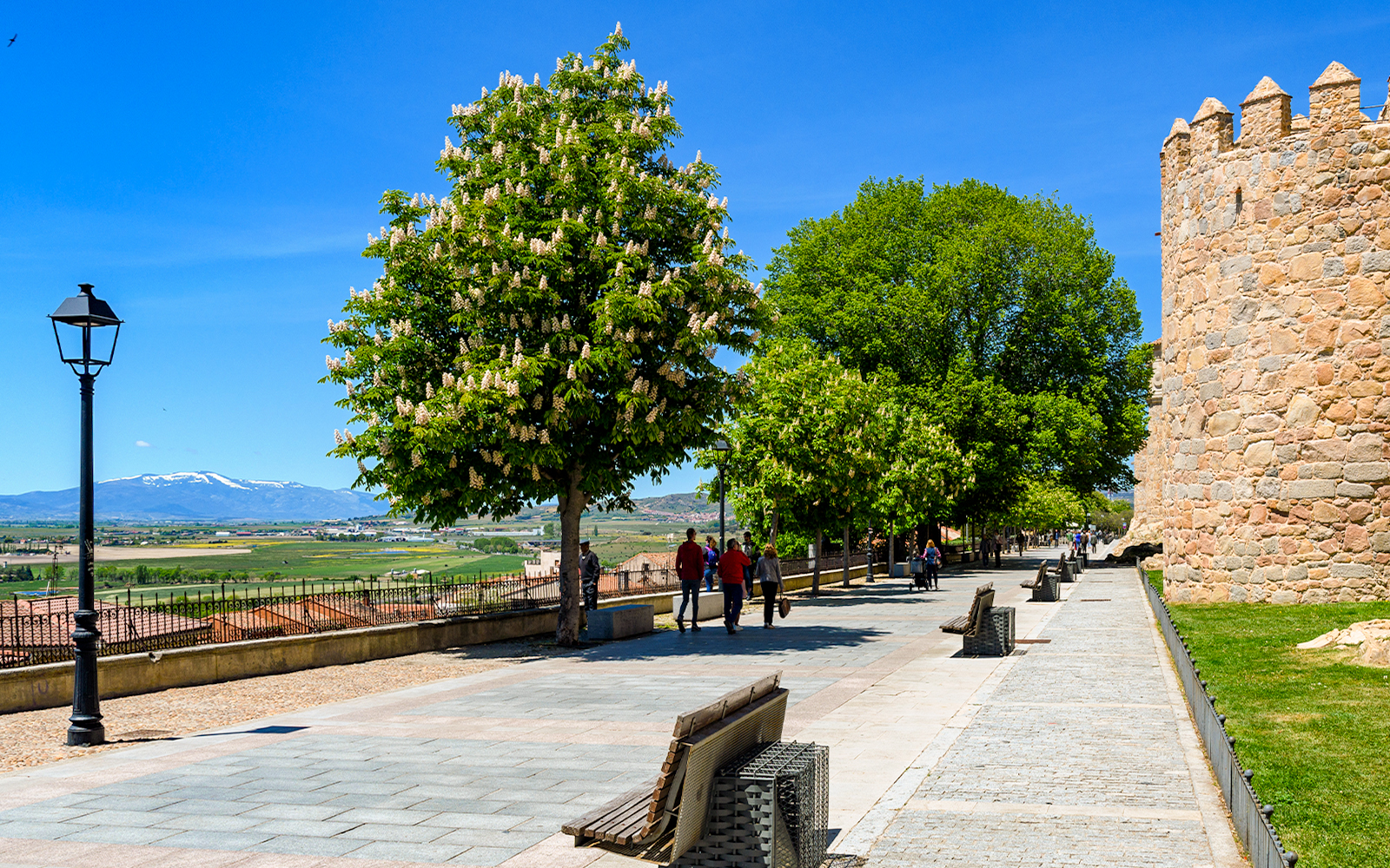 Walkway along the Walls of Ávila with trees and distant mountains, Ávila, Spain.