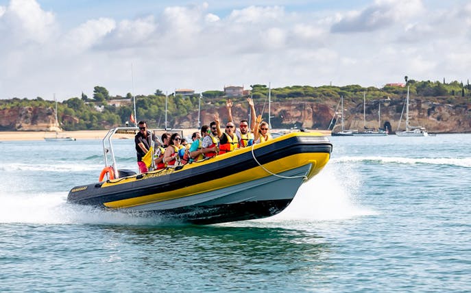 Boat tour with passengers near Algarve cliffs during Full-Day Walking Tour from Portimão.