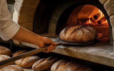 Baker removing fresh bread from a wood-fired oven during a cooking class in Rome.