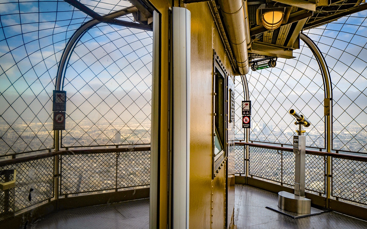 Eiffel Tower observation deck with telescope overlooking Paris.