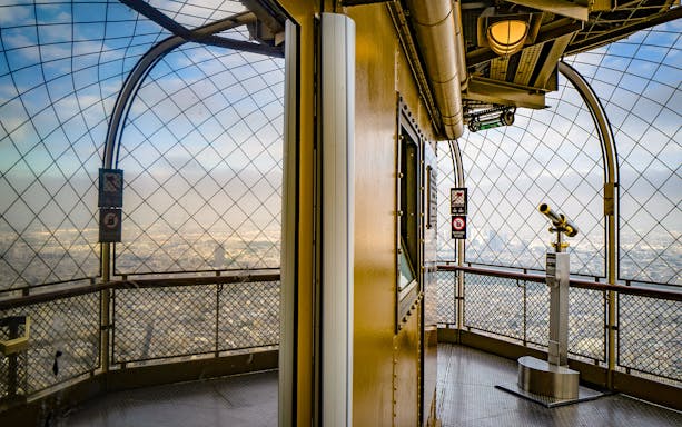 Eiffel Tower observation deck with telescope overlooking Paris.