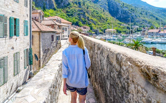 Guest walking along Kotor's historic walls with view of bay and boats during Montenegro tour.