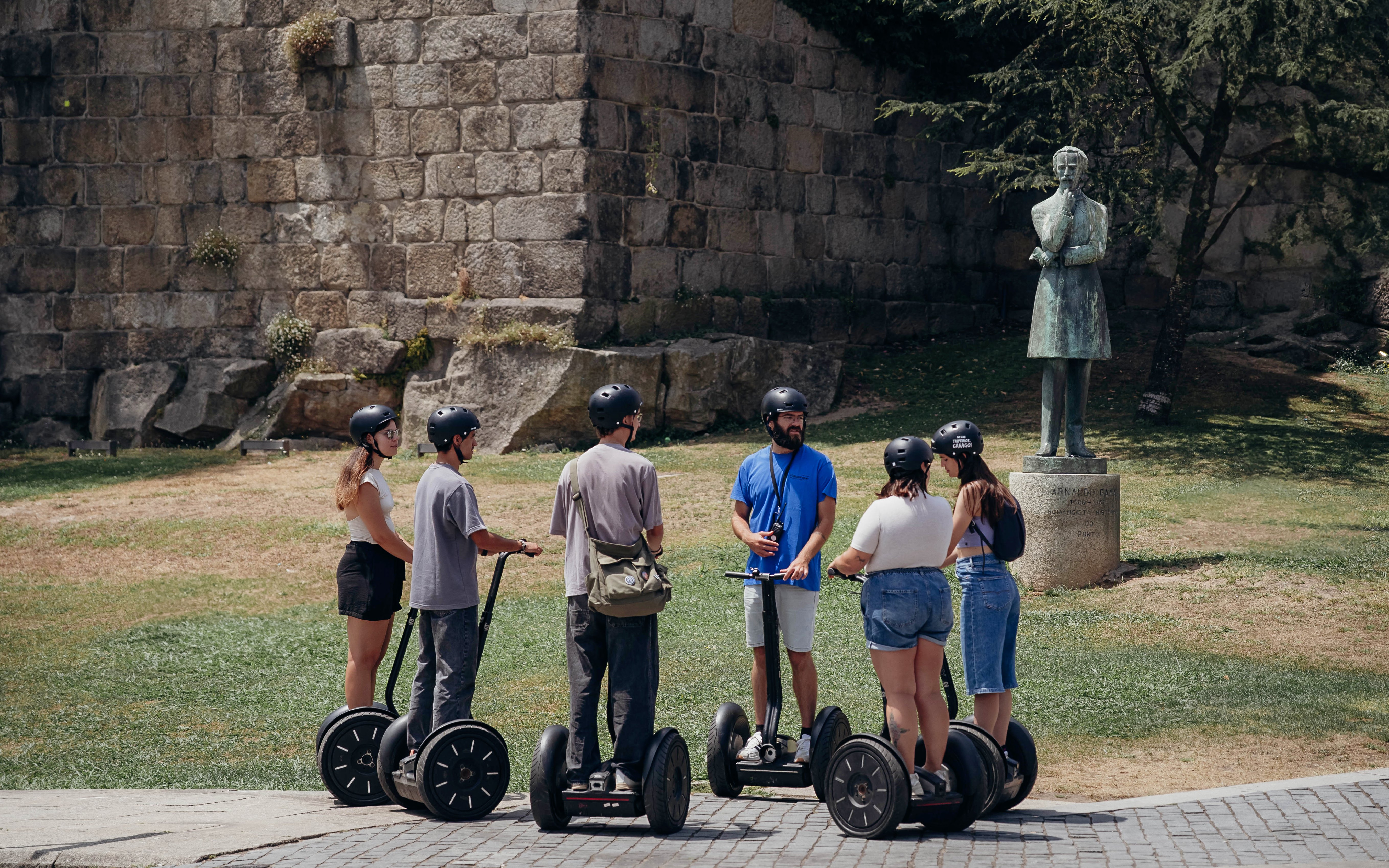 Tourists with guide on Segway tour near statue in Porto, Portugal.