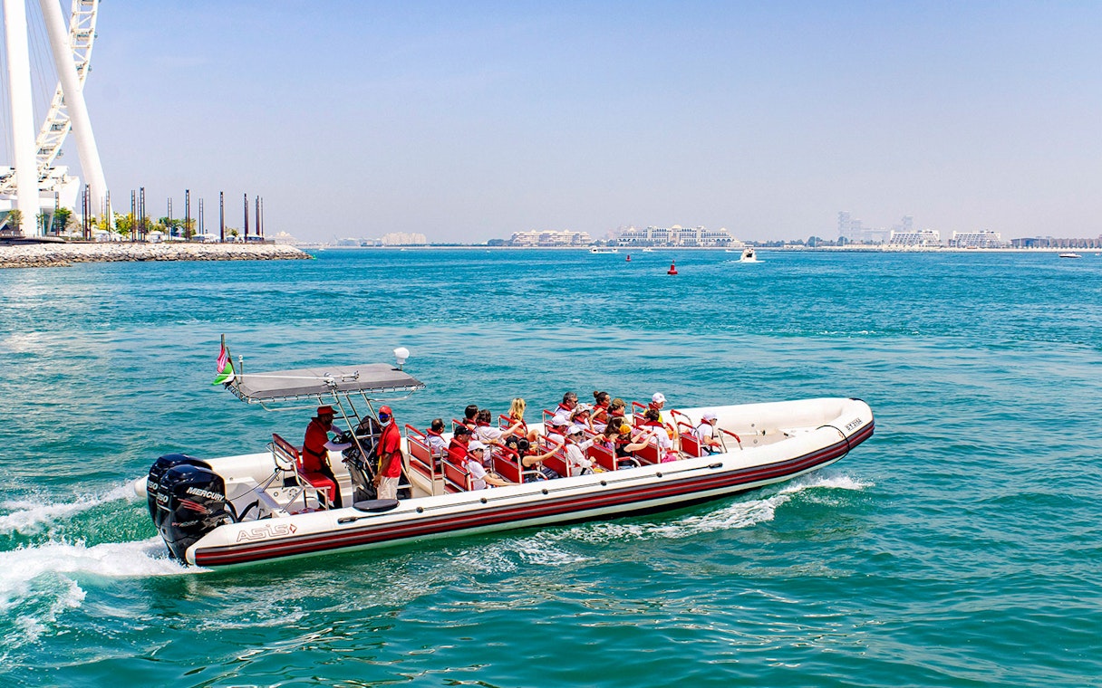 Speedboat with tourists cruising Dubai Marina near Ain Dubai.