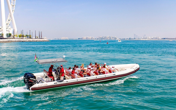 Speedboat with tourists cruising Dubai Marina near Ain Dubai.