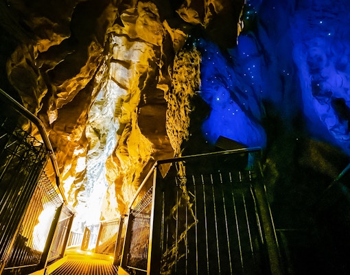 Walkway inside Ruakuri Cave with illuminated rock formations, Waitomo, New Zealand.