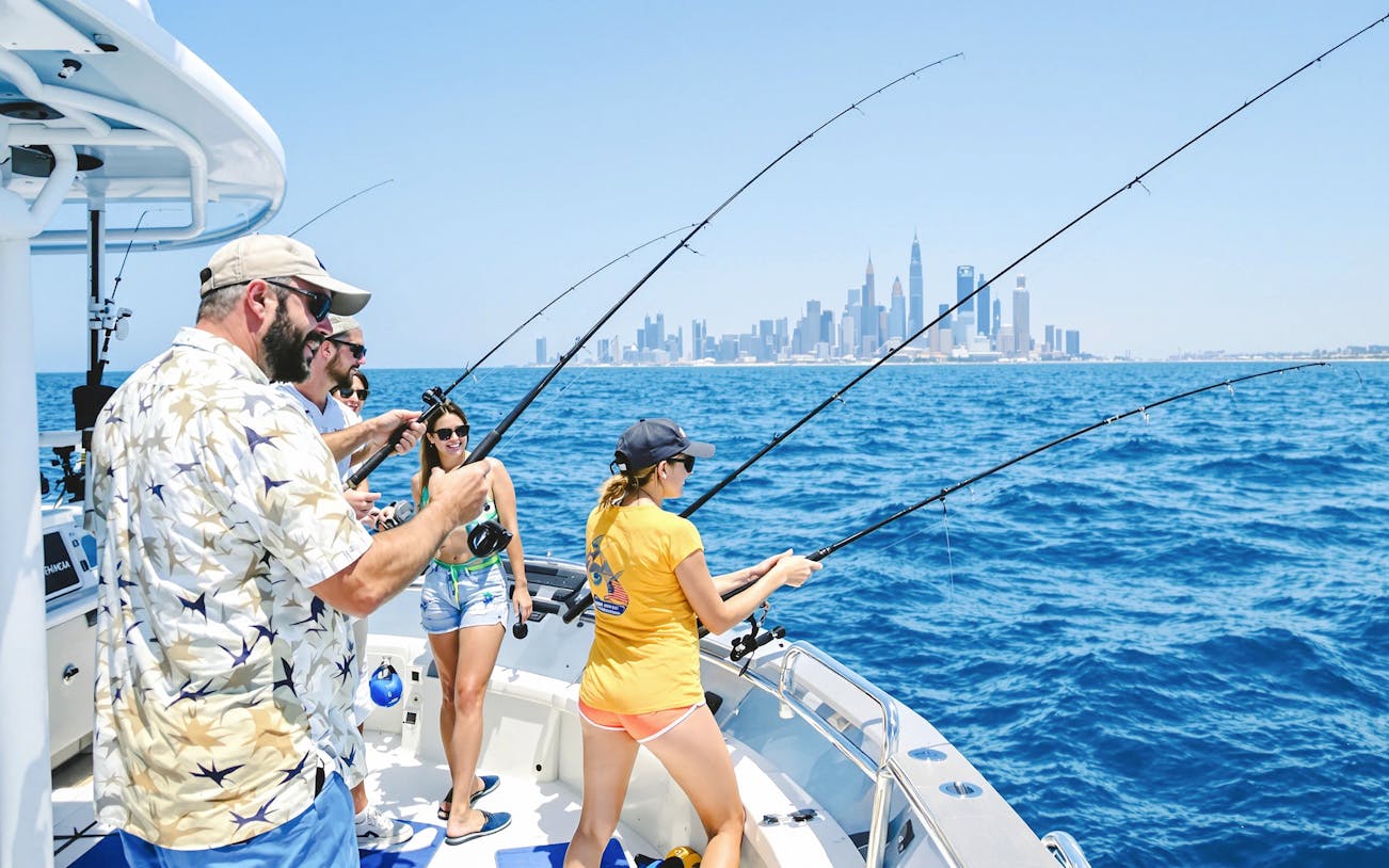 Friends fishing on a boat with Dubai skyline in the background.