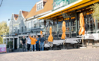 Tourists walking past cafes in Volendam during a guided tour.