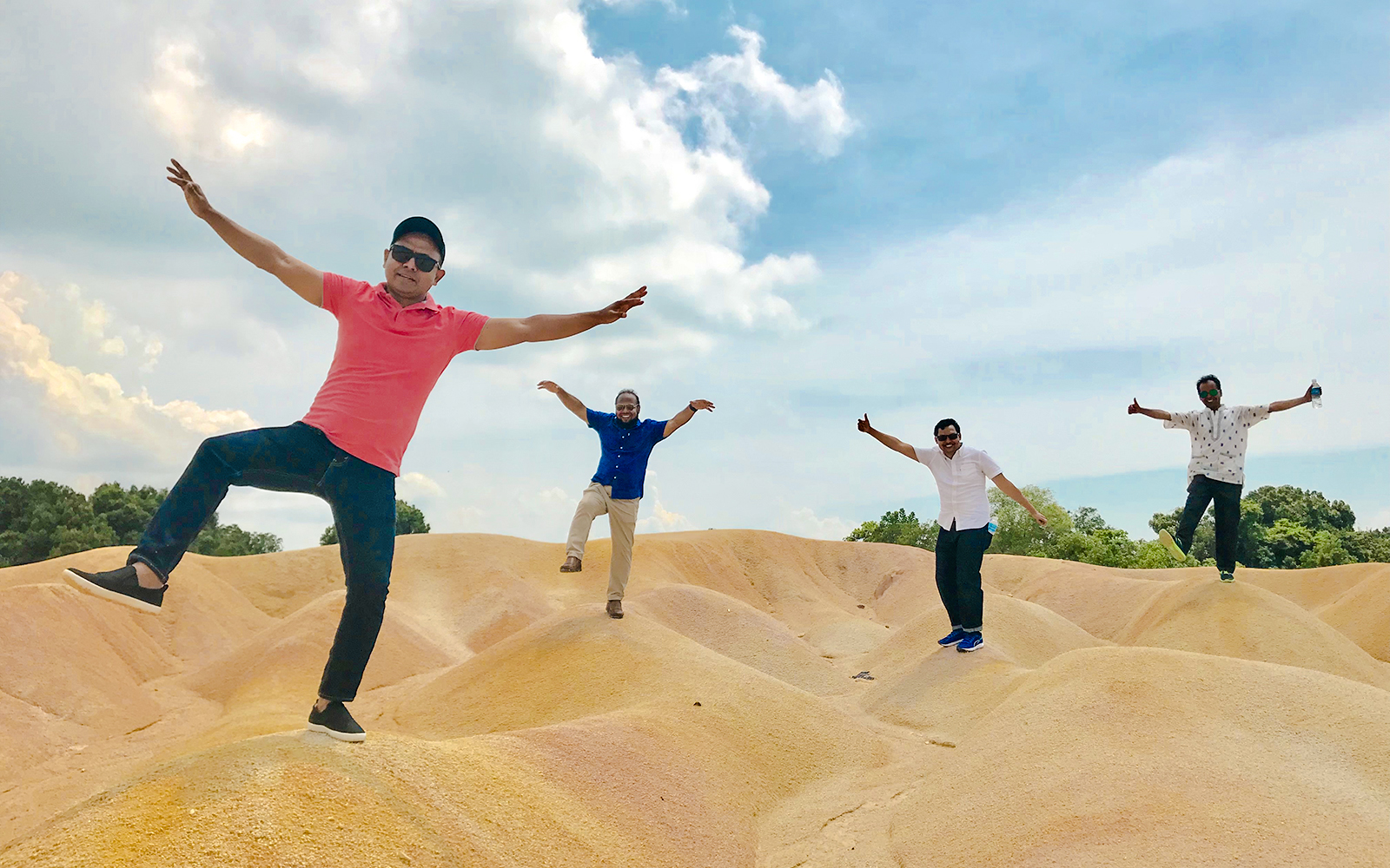 Tourists posing playfully on sand dunes at Bintan Mini Desert.